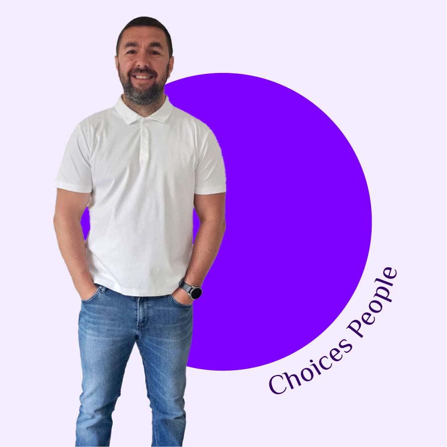 Choices Director Stephen Kearley stands in a white polo shirt and blue jeans against a bright purple circle on a light purple background, encircled by the words Choices People.